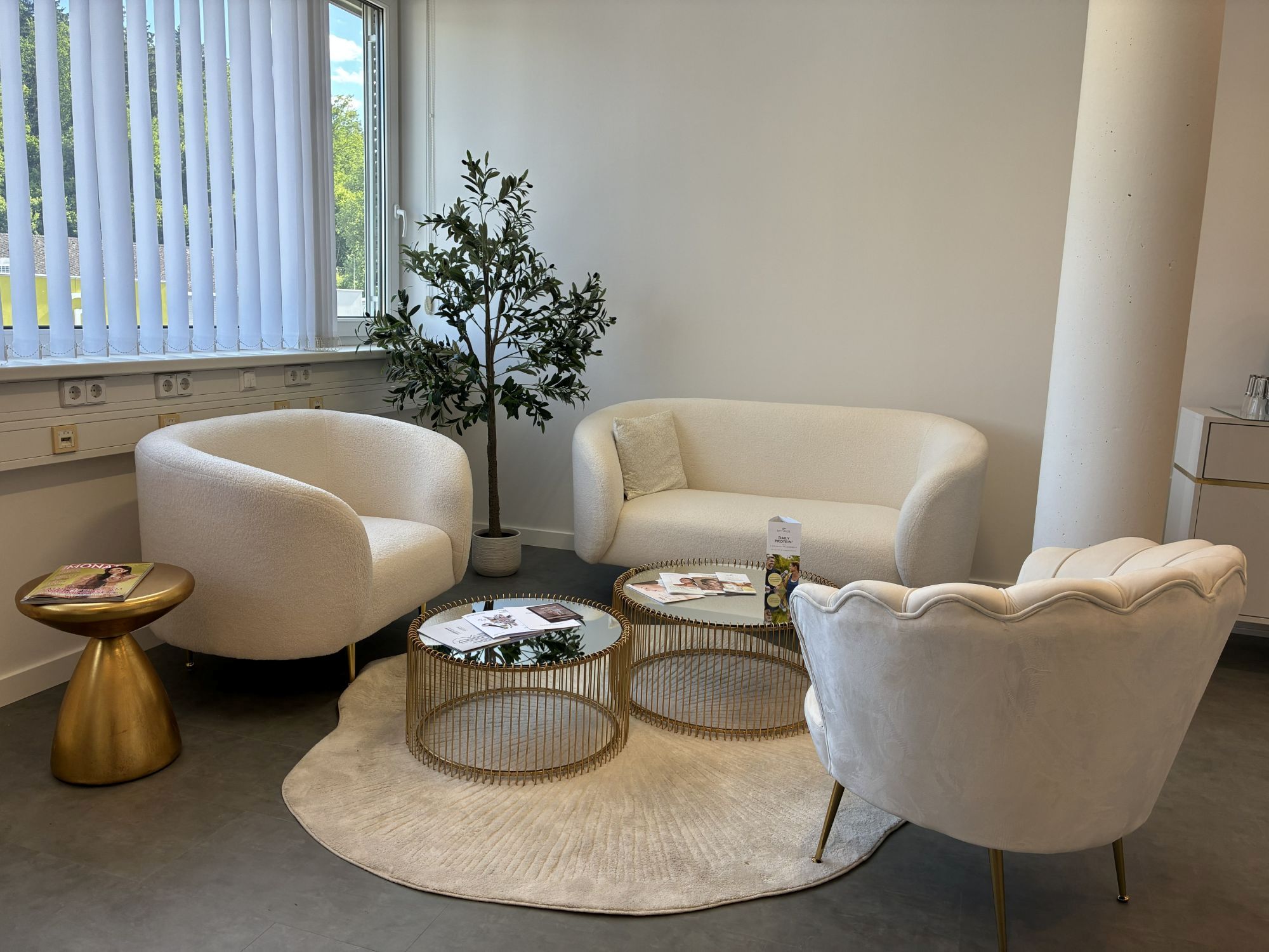Lounge mit Bouclé-Sesseln und goldenen Tischen